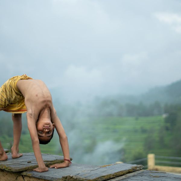 Person meditating outdoors with a serene natural landscape in the background.
